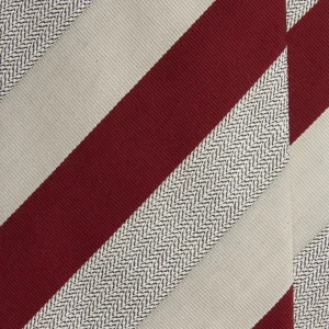 A close-up of a red silk jacquard tie in cream stripes with a herringbone band