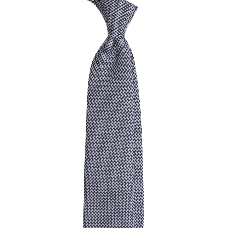 A navy and white silk jacquard tie in houndstooth, tied in a knot