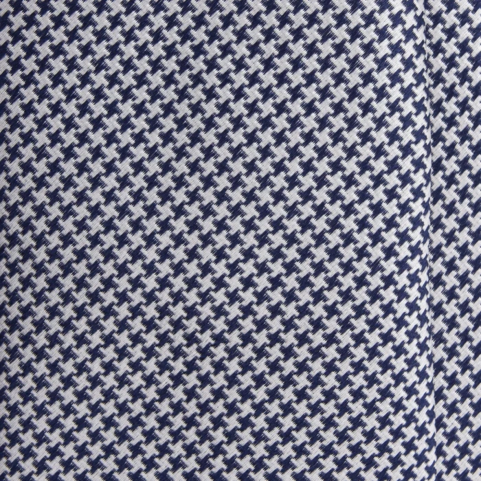 A close-up of a navy and white silk jacquard tie in houndstooth