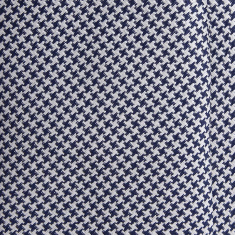 A close-up of a navy and white silk jacquard tie in houndstooth