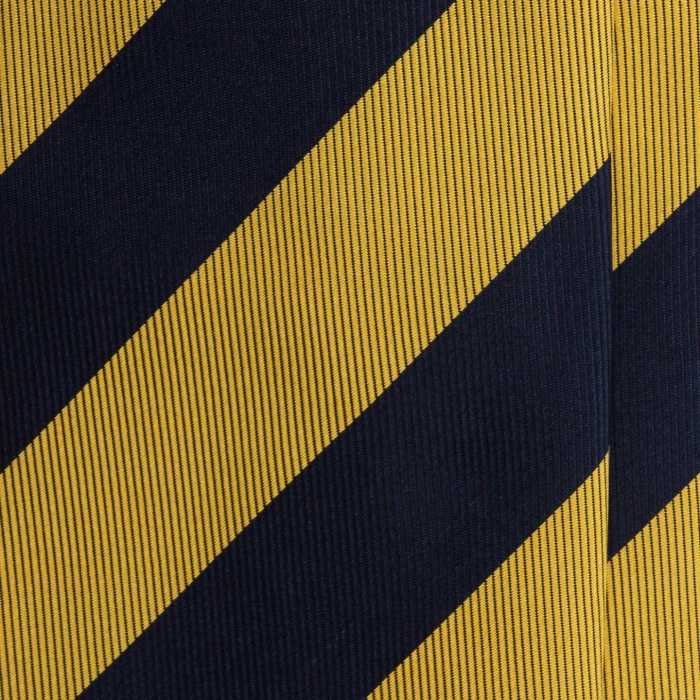A close-up of a navy silk jacquard tie in wide mustard stripes