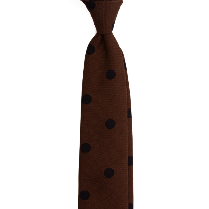 A brown silk tie with large navy polka dots, tied in a knot