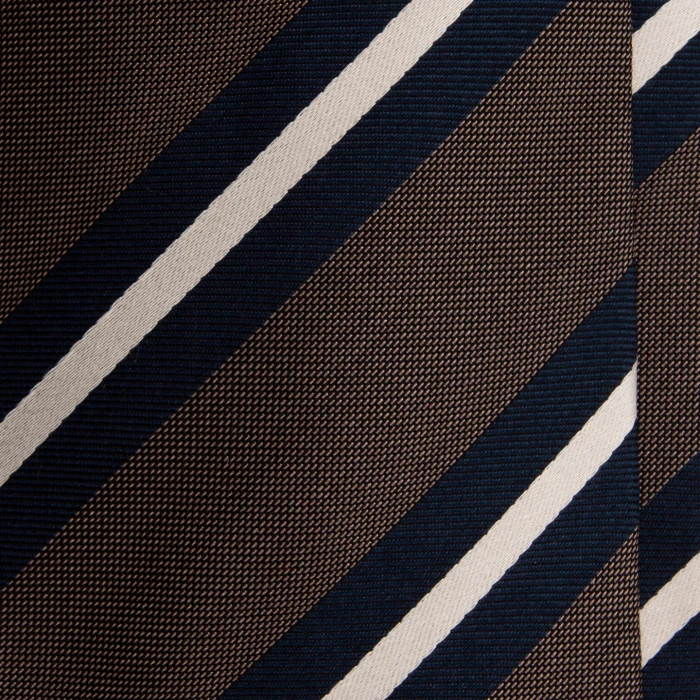 A close-up of a taupe silk jacquard tie with navy and cream stripes