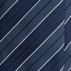 A close-up of a navy silk jacquard tie with steel blue stripes and white pinstripes