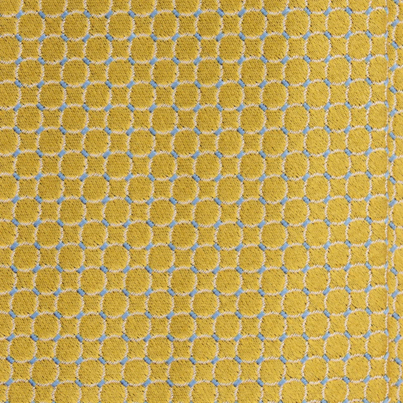 A close-up of a yellow silk jacquard tie with a circle pattern and blue accents